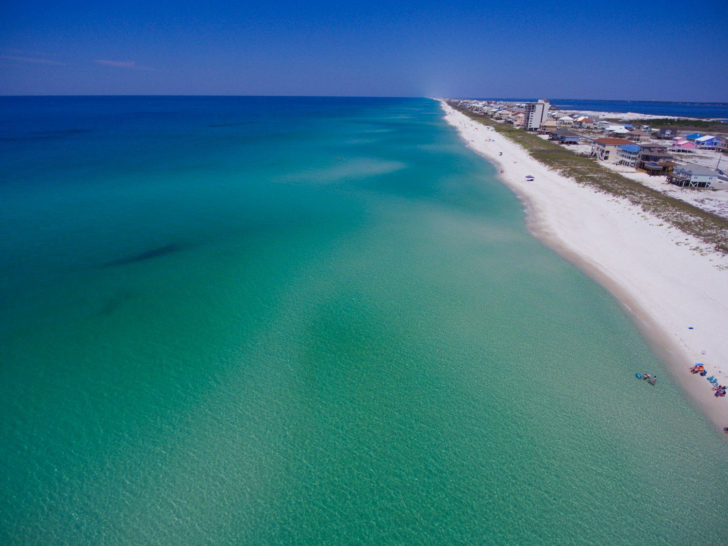 Turquoise Gulf water meeting a white sand beach, seen from above
